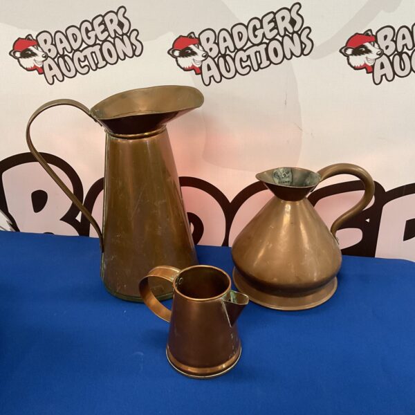 Set of three vintage copper jugs with aged patina.
