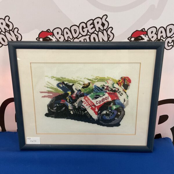 Framed embroidery of a vibrant superbike in a racing scene.