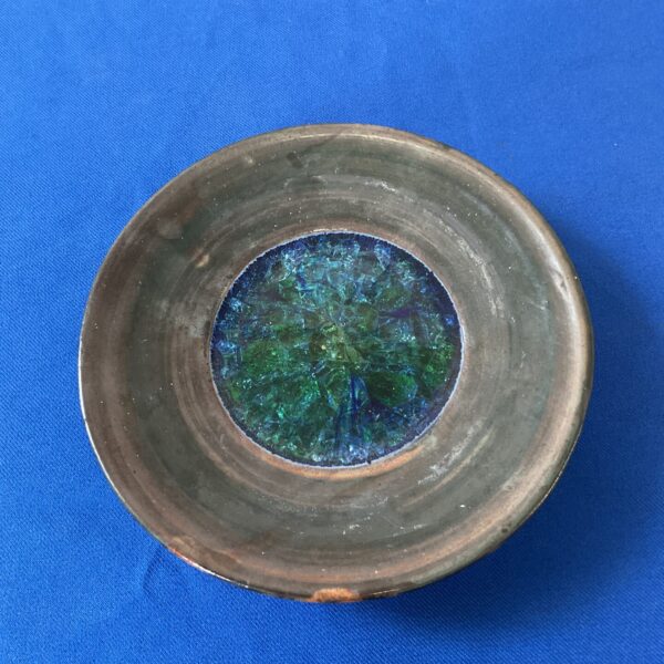 Marc Folkstone studio pottery dish with stained glass centre on blue background.
