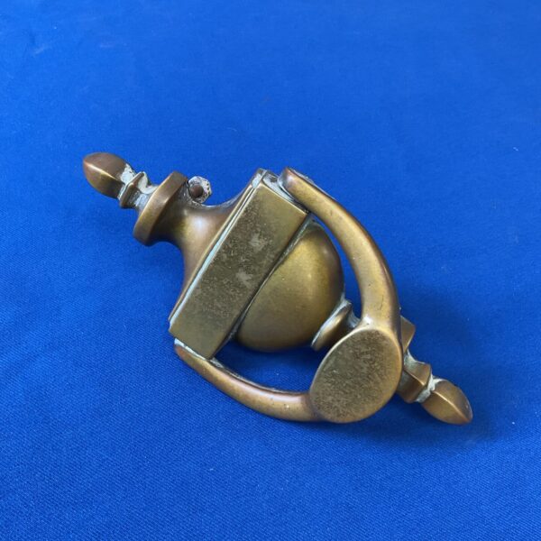 Vintage brass door knocker with ornate detailing.
