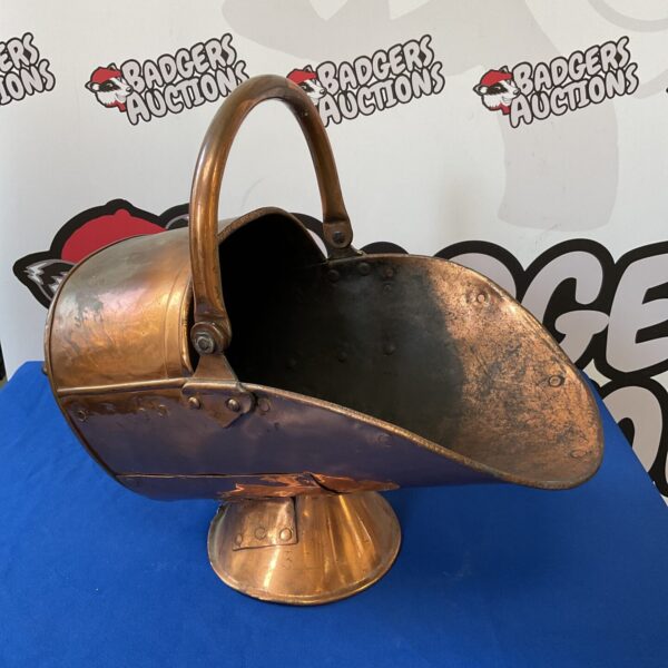 Antique copper coal scuttle with curved handle and patina.