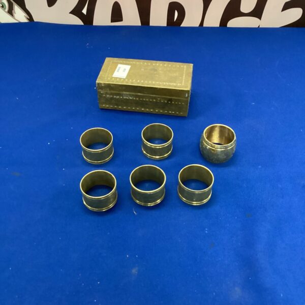 Set of four vintage brass napkin rings on a dark surface.