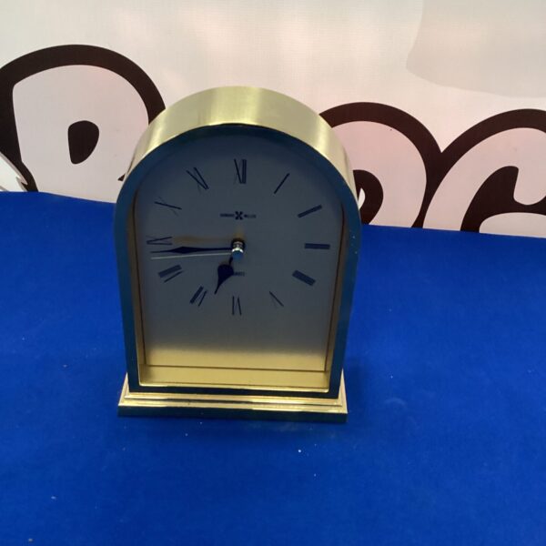 Gold-toned Howard Miller mantle clock on a dark surface.