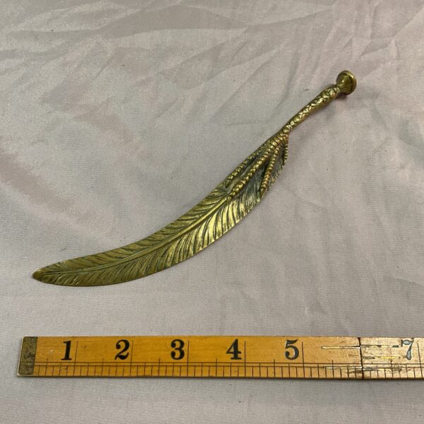Vintage brass paper knife with bird claw and feather design.