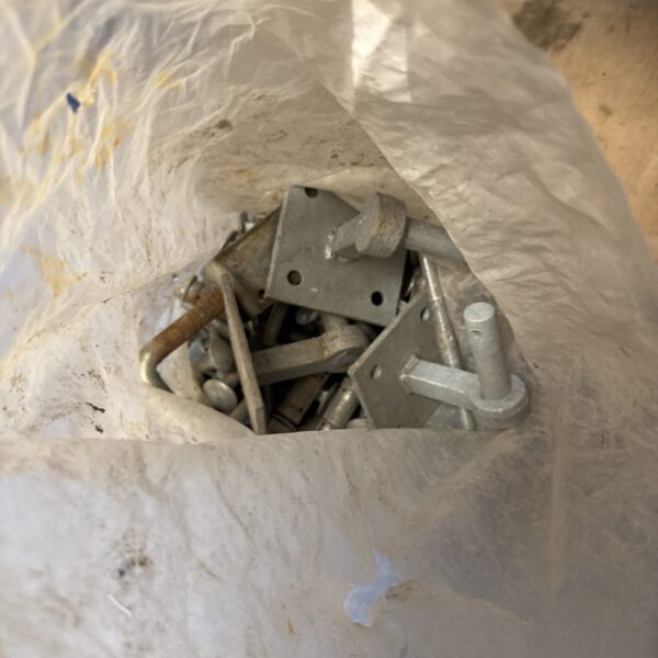 Collection of used metal gate hinges and large bolts.