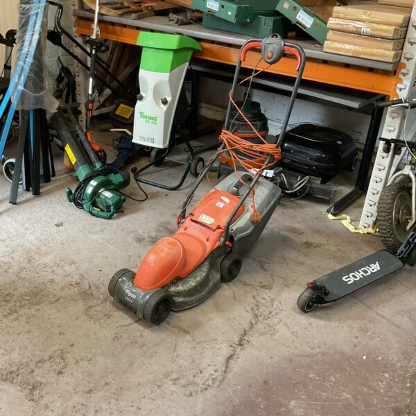 Side view of a used Flymo electric lawn mower in a garage.
