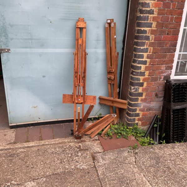 Pair of vintage wooden artist easels in a garden setting.