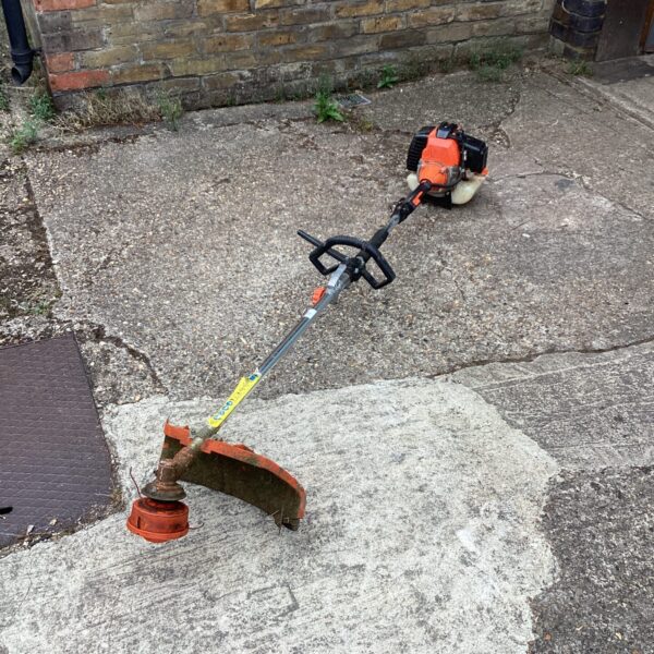 Petrol garden strimmer with a two-stroke engine, ideal for lawn maintenance.