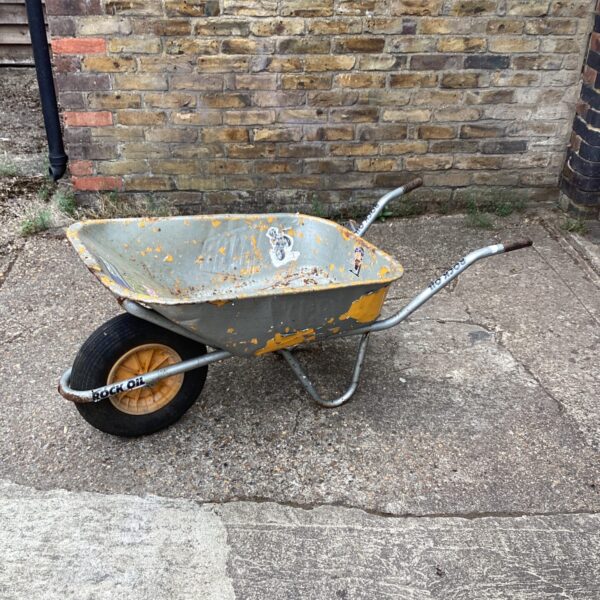 Weathered vintage metal wheelbarrow, a rustic garden tool.
