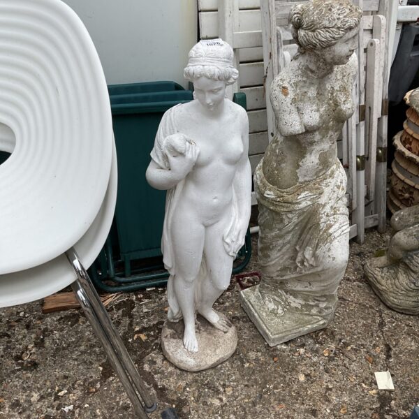 Weathered stone garden statue of a nude lady with a dove.
