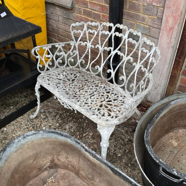 Vintage aluminium garden bench with floral detailing in a garden setting.