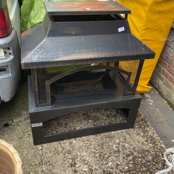 Side view of a metal garden log burner with chimney.