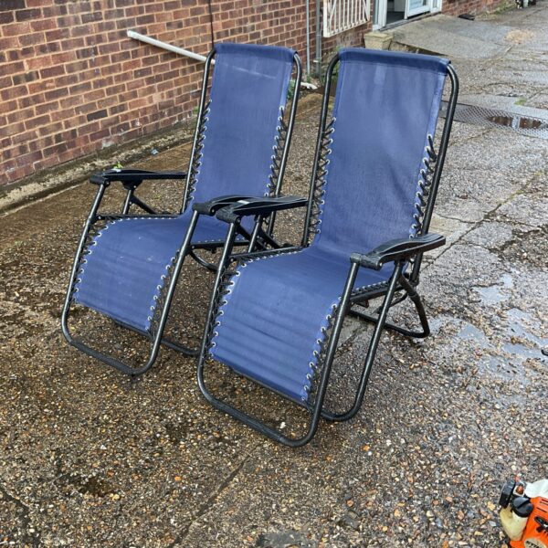 Two blue garden sun loungers in a garden setting.