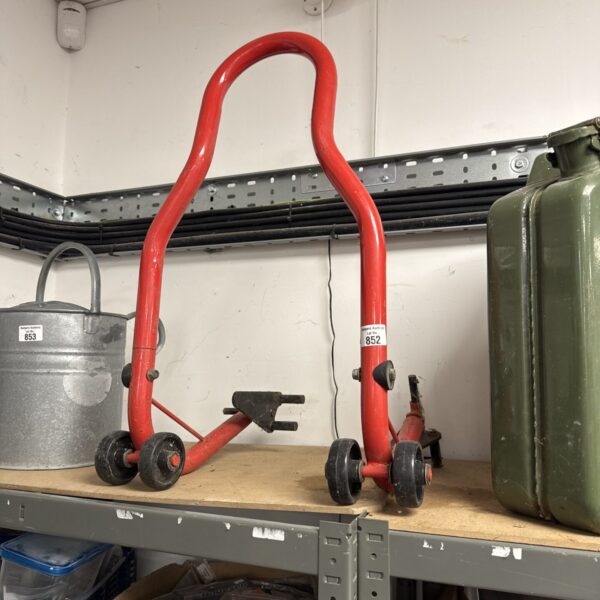 Red motorcycle lift stand for rear wheel maintenance.
