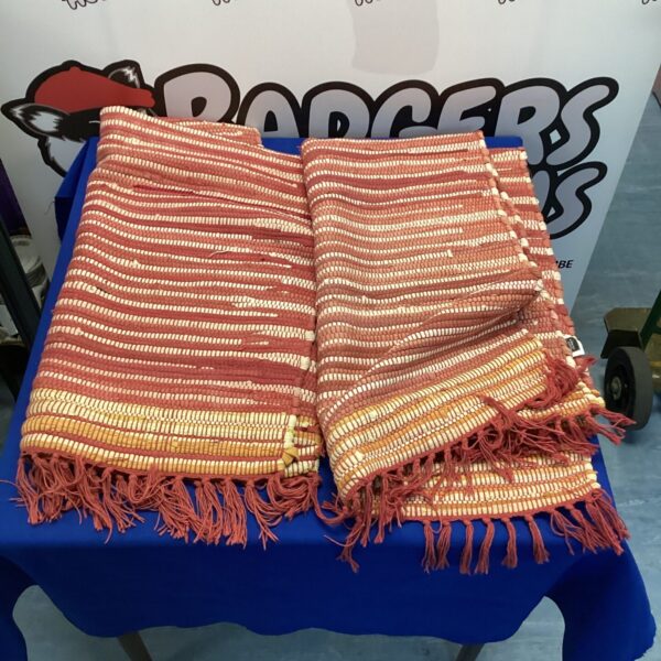 Two red Karkton House rugs with woven texture and fringe detail.
