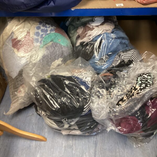Four large bags filled with mixed clothing lots for resale.
