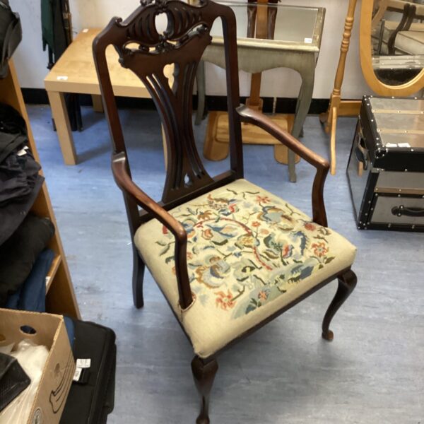Antique armchair with patterned upholstery and carved wood frame.