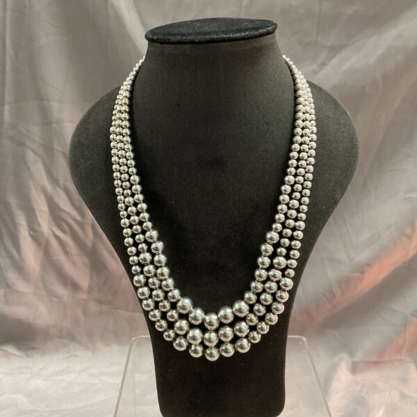 Graduated silver bead necklace on a display bust.