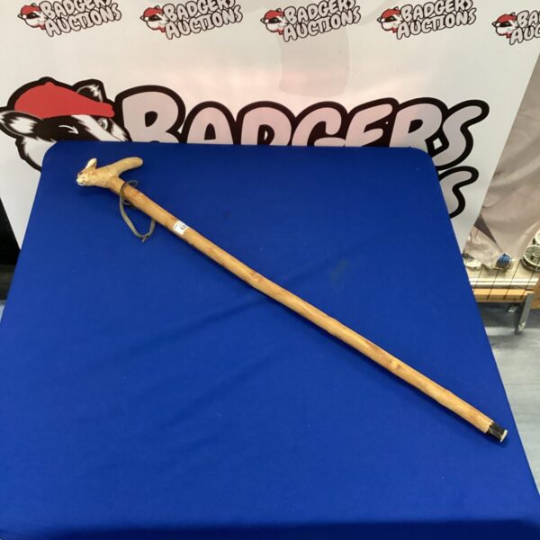 Vintage rabbit walking stick displayed on blue fabric.