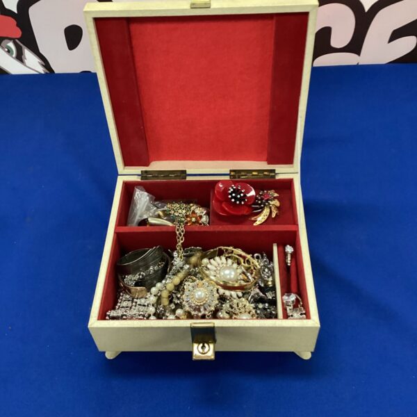 Cream musical jewellery box with jewellery inside.