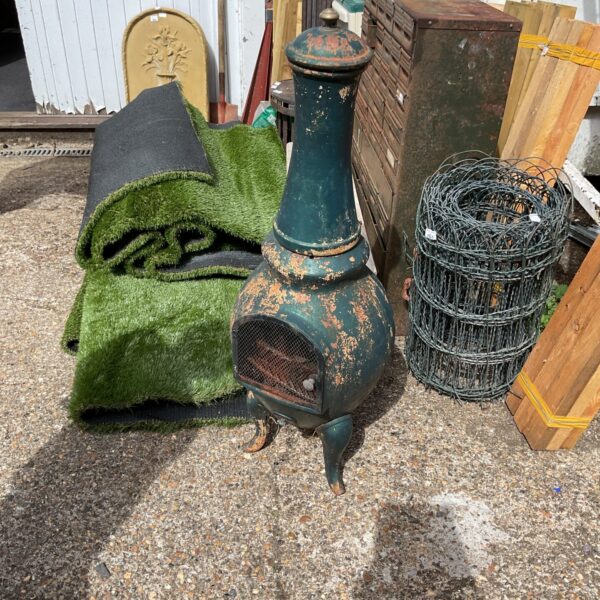 Rusty cast iron garden chiminea with green grass nearby.