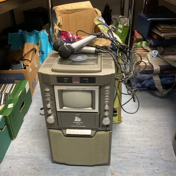 Vintage singing machine karaoke system with microphones and CDs.