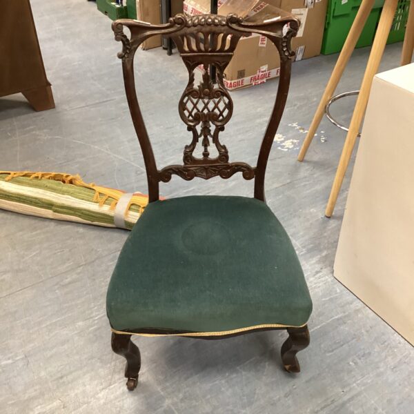 Antique mahogany nursing chair with green upholstery.