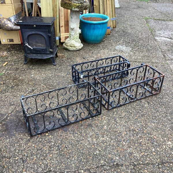 Vintage wrought iron wall planters displayed outdoors, ideal for garden decor.