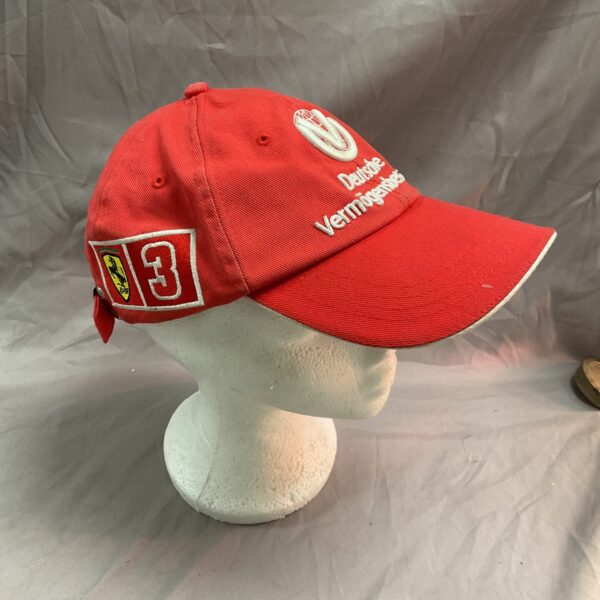 Red Ferrari Michael Schumacher cap displayed on a mannequin head.