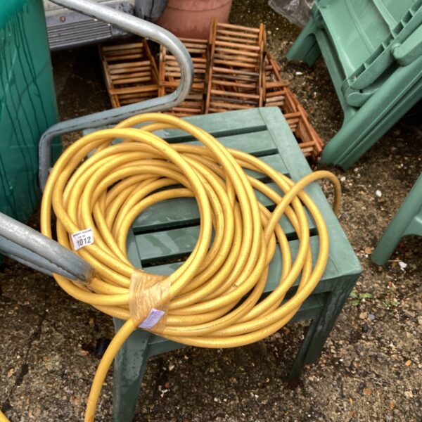 Vintage yellow rubber garden hose coiled on a green surface.