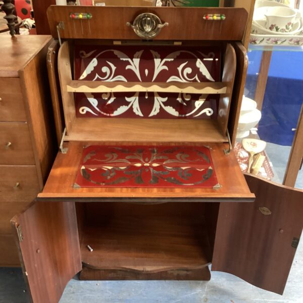 Front view of a vintage walnut cocktail cabinet with patterned details.