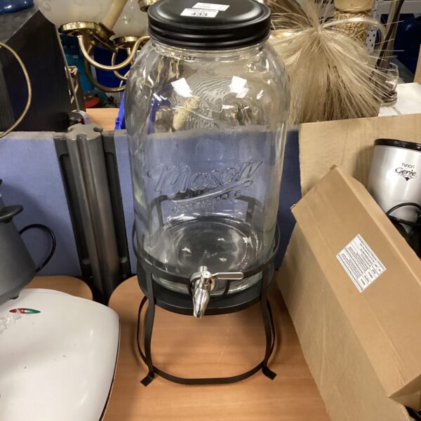 Clear glass mason jar drinks dispenser with black tap.