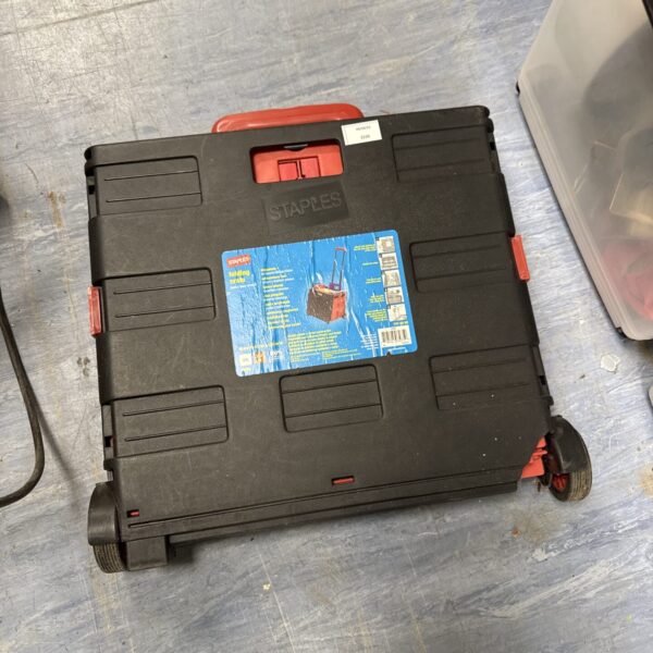 Red and black Staples folding wheeled crate for portable storage.