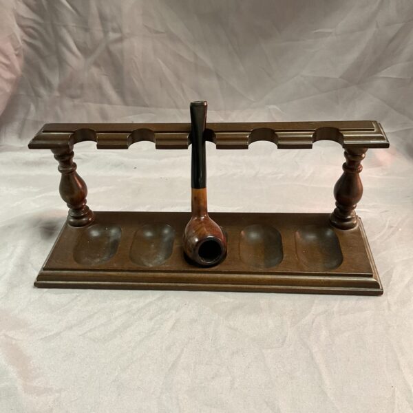 Vintage wooden pipe rack holding a pipe.