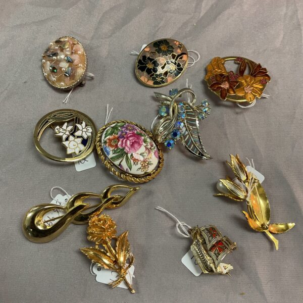 Assorted vintage brooches in a jewellery lot, diverse styles.