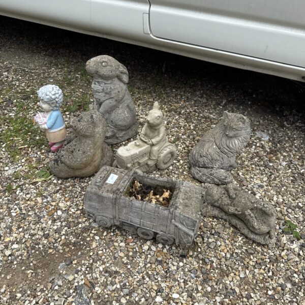 Assorted vintage concrete garden ornaments including rabbits and cats.