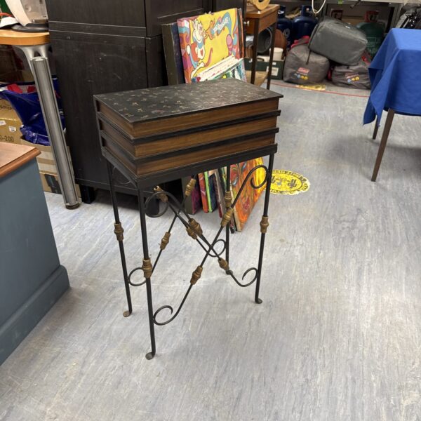 Vintage wrought iron table with book-style design in a room setting.