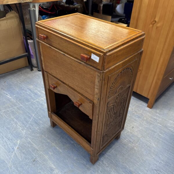 Front view of a vintage carved oak cabinet with a single drawer.
