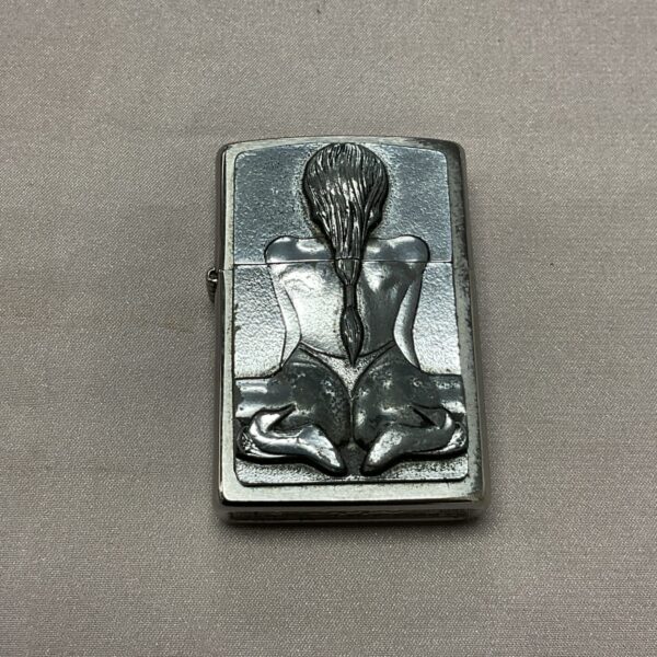 Vintage Zippo lighter with pin-up girl engraving on metal casing.