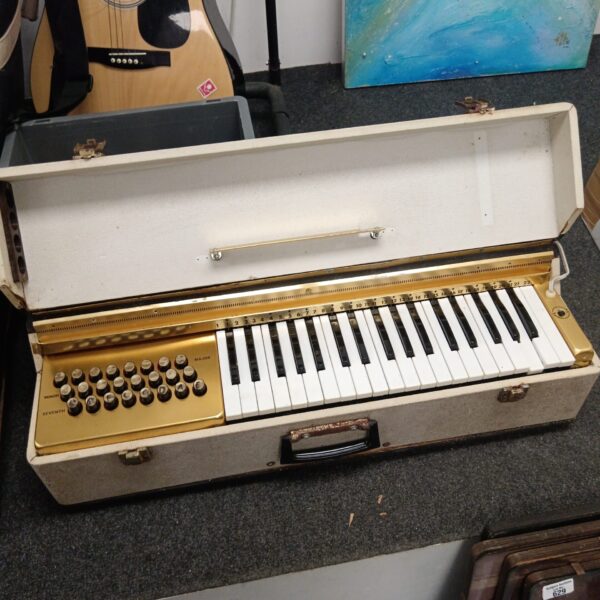 Vintage electric travel organ with white and gold keys.