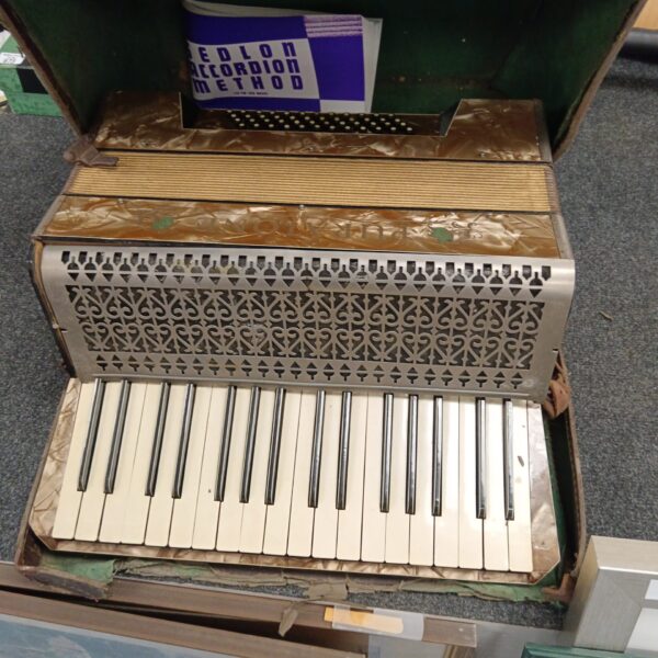 Front view of a vintage Puratone accordion needing restoration.