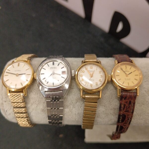 Four vintage ladies’ watches with gold-tone bracelets and varying dial designs.