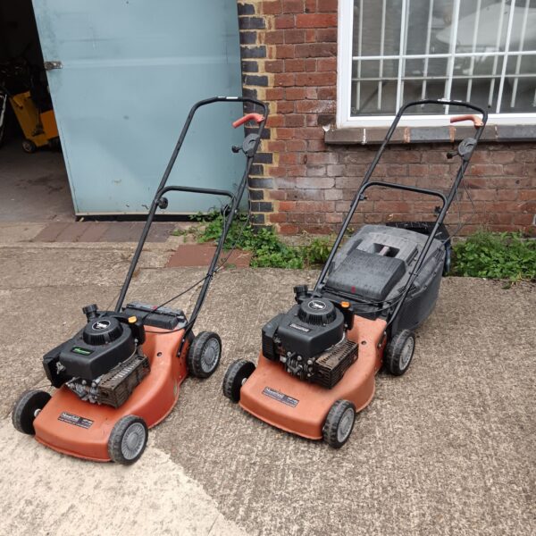 Two Mountfield V35 petrol lawnmowers in a garden setting.