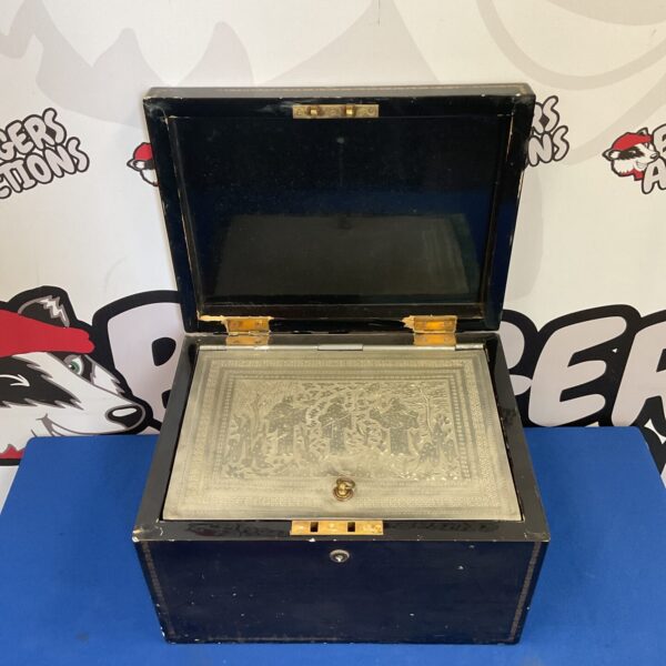 Open antique Chinese tea chest with embossed metal interior.
