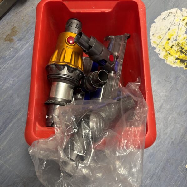 Yellow Dyson cordless vacuum body with attachments for cleaning.
