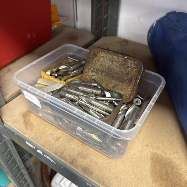 Assorted metal drill and router bits in a plastic container.