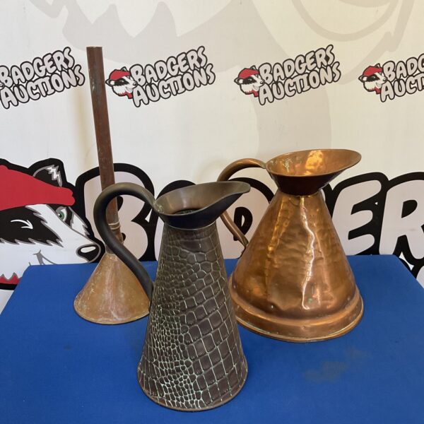 Vintage copper pitchers and funnel with aged patina.