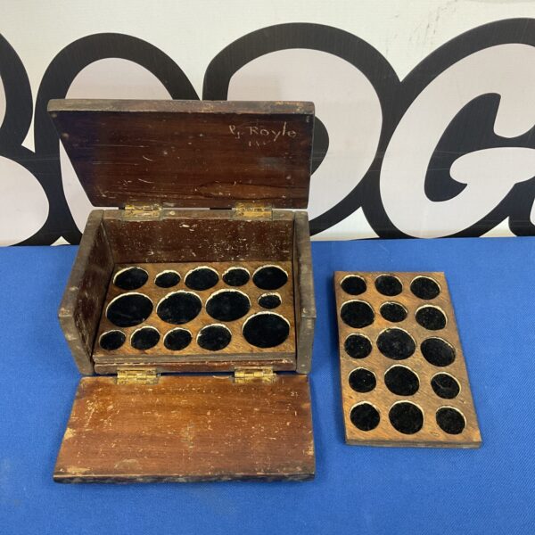 Vintage wooden coin collectors box with circular recesses for coins.