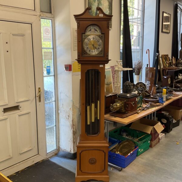 Antique grandfather clock with weights and pendulum in a room.