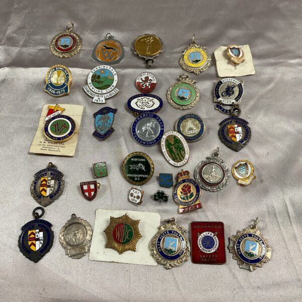 Vintage collection of enamel pin badges and medals, including sports themes.